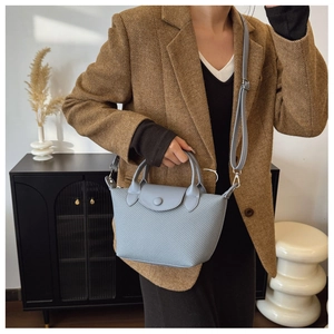 Detail of grey-blue woven leather mini bag showing flap closure and thin shoulder strap