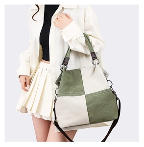 Detail of green and beige canvas tote bag with brown straps and metal hardware