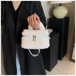 Detail van de pluizige witte bucketbag met zilveren ritsen en een zachte harige textuur