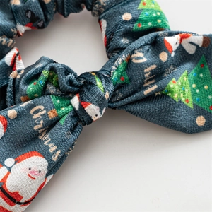 Detail of green velvet Christmas scrunchie with Santa prints and gold lettering