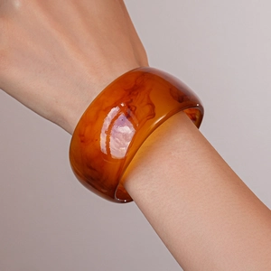 Close-up of amber resin geometric wide bangle with tortoise pattern texture on wrist