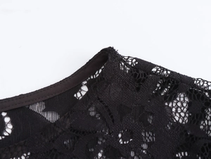 Close-up of intricate black lace patterns and solid trimmed neckline on a bodycon dress
