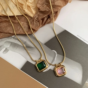 Detail of square emerald and pink crystal pendant necklaces on gold snake chains