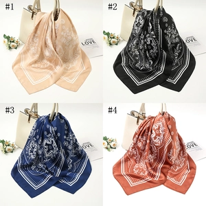 Detail of four paisley pattern silk-like scarves tied on a white leather handbag
