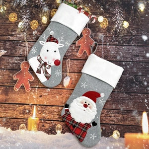 Close-up of grey felt Christmas stockings with Santa and reindeer hanging on wood wall