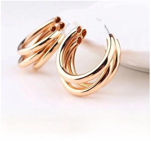 Macro shot of gold plated triple-layer C-shape hoop earrings on a ceramic dish