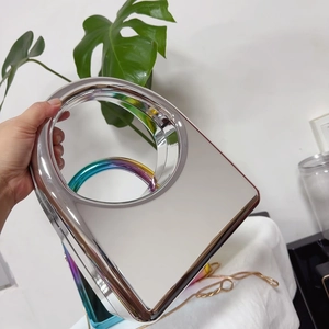 Detail of silver mirror evening bag with circular hollow handle and rainbow electroplating