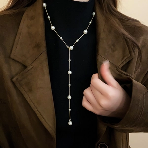 Close-up of a French style golden Y-shaped pearl lariat necklace on a model