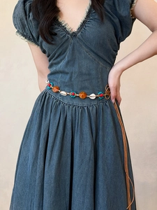 Détail de la chaîne de taille ethnique avec coquillages et perles sur robe en jean