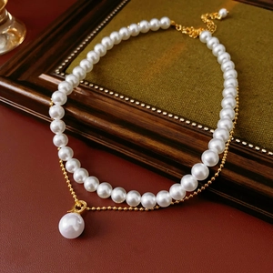 Detail of double-layer gold-plated necklace with white pearls on a vintage background
