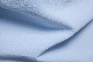 Close-up of light blue cotton linen shirt fabric showing fine plain weave texture