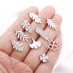 Detailed close-up of 10 silver stainless steel leaf pendants held in a hand for size