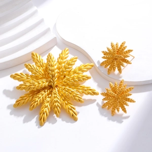 Golden wheat-shaped brooch and earrings set displayed on minimalist white geometric props