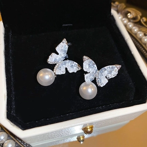 Detail of silver butterfly earrings with white pearls and sparkling crystals in a jewelry box