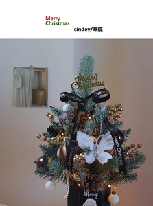 Detail of mini Christmas tree with LED lights, golden berries, and Merry Christmas ribbons