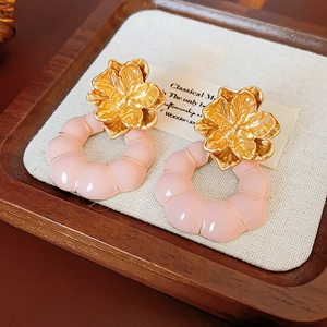 Détail de boucles d'oreilles fleur vintage dorées avec anneaux en résine rose texturée
