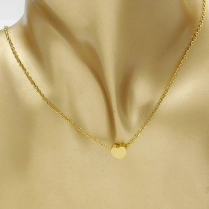 Vue détaillée d'un collier avec pendentif cœur doré poli porté sur le cou d'un mannequin