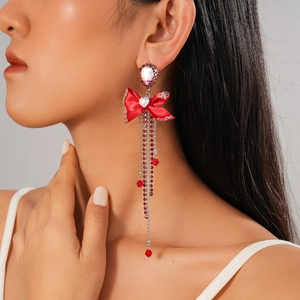 Close-up of red ribbon bow earrings with cascading crystal fringe on female model