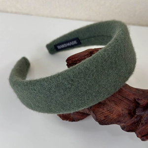Detailed close-up of dark green wool headband featuring a white HANDMADE label on interior