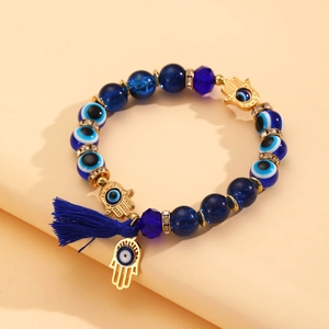Detail van de boheemse kralenarmband met Hamsa-bedeltjes en een blauwe zijden kwast