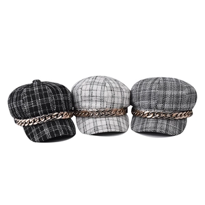 Plaid newsboy caps in black, white, and grey with gold chain accents and tweed texture