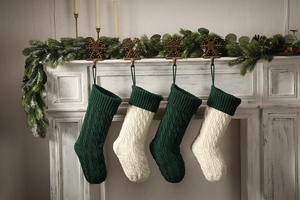 Classic knitted Christmas stockings in green and white hanging on a cozy white fireplace