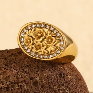 Detail showing gold floral embossed signet ring with crystals on brown stone
