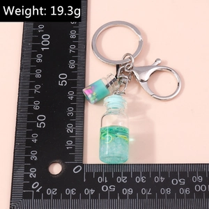 Detail view of fruit bottle keychain with green liquid and weight 19.3g measurement