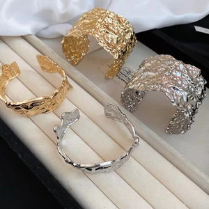 Detail of gold and silver irregular crinkled metal bangles on a beige velvet display tray