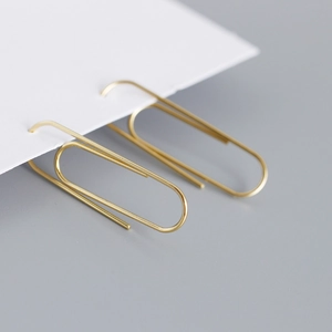Detail shot of golden safety pin earrings displayed on a white card for a minimalist look