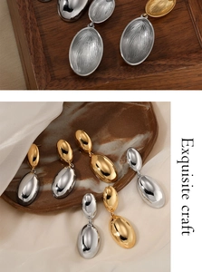 Exquisite craft detail of gold and silver teardrop earrings on a wooden tray