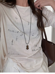 Close-up of minimalist resin gourd pendant necklace worn on a black cord strap