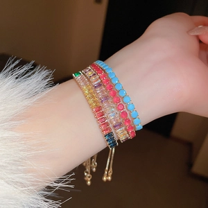 Détail de bracelets dorés ajustables avec cristaux bleus et magenta et pierres de zircon