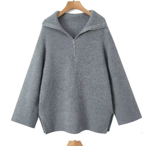 Détail du pull en maille côtelée grise avec demi-zip, col montant et fentes sur les côtés