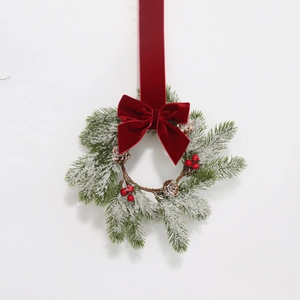 Christmas wreath with snowy pine needles, red berries, cones and red velvet bow