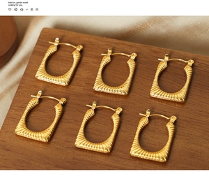 Macro shot of gold-plated square earrings featuring unique textured metal finish
