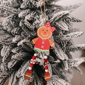 Detail showing wooden gingerbread man ornament hanging on a snowy Christmas tree branch