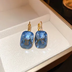 French style gold earrings with rectangular blue gemstones in a luxury jewelry box