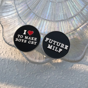 Macro detail of round black enamel pins with silver motivational slogans in a glass dish