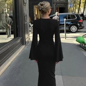 Gros plan sur la courbe du dos et les larges manches évasées de cette robe longue en maille