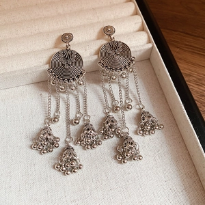 Close-up of vintage silver hoop earrings with metal fringe tassels and small bells on velvet