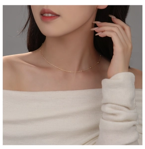 Close-up of minimalist gold s925 sterling silver beaded necklace worn on neck