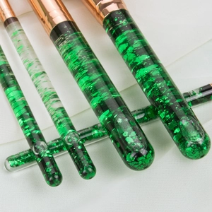 Close-up of 7 makeup brushes with green glitter liquid handles and rose gold ferrules