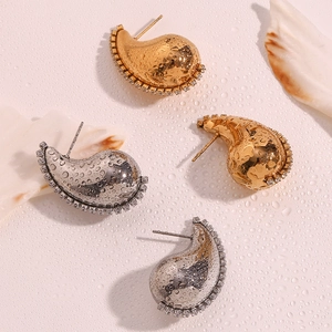 Détail de boucles d'oreilles goutte dorées et argentées ornées de zircons scintillants
