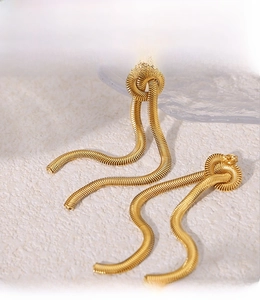 Detailed macro view of 18K gold-plated knot earrings with elegant long snake chain tassels
