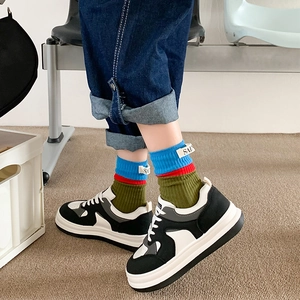 Close-up of stylish color-block crew socks with embroidered letter tag detail