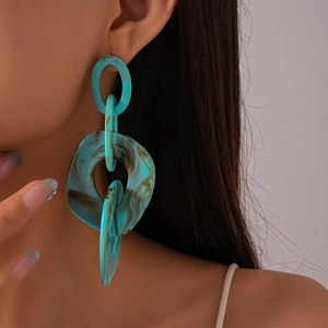 Close-up of model wearing large oversized blue acrylic hoop earrings with tortoiseshell texture