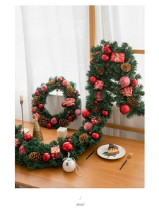 Detail of Christmas wreath and garland set with pine cones and red ornaments on a wooden table