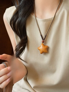 Close-up of minimalist wooden star pendant on braided rope necklace with wooden bead detail