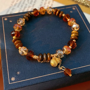 Détail macro de perles d'Oeil de Tigre et de pendentifs dorés sur un bracelet perlé